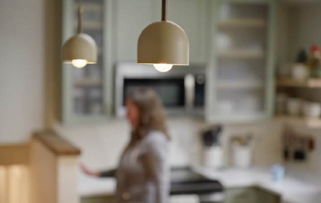 A woman turns on lights in a kitchen
